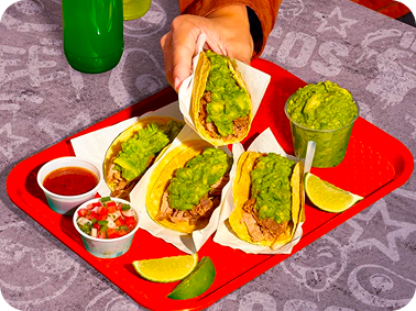 Tray of tacos topped with fresh guacamole